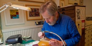 Peter Lawrence engraving wood in his home