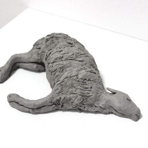 A grey sculpture of a sheep lying down.